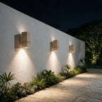 Tres arandelas de travertino em sequencia iluminando muro e caminho de entrada